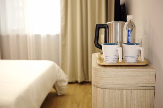 A bed and a pair of cup of coffees in a hotel bedroom