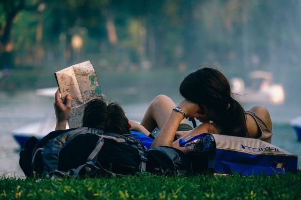 Two travellers looking at a map on the grass